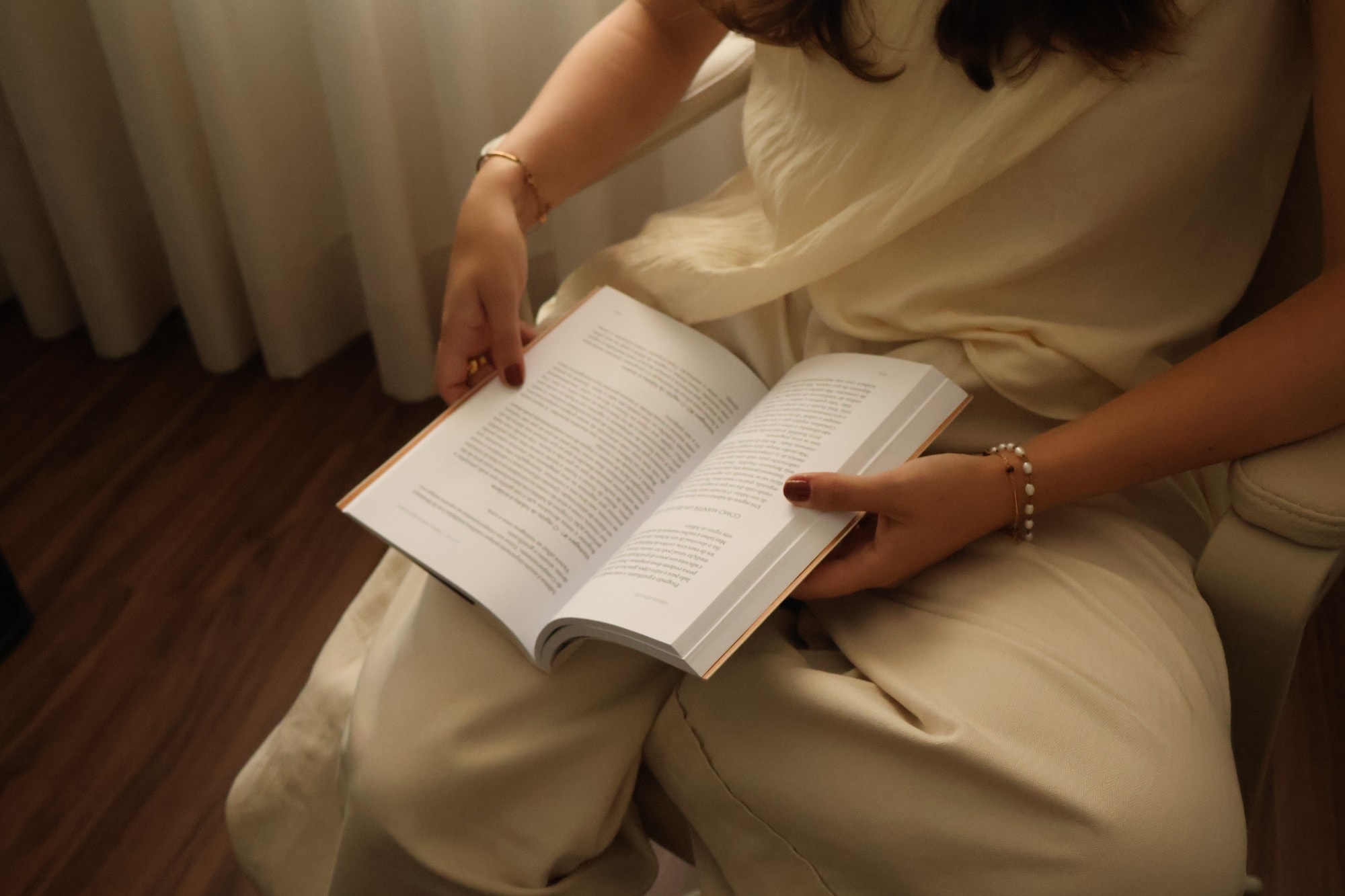 Mulher sentada num cadeirão a ler um livro aberto no colo